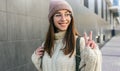 Happy student woman smiling, wearing sweater and trendy transparent eyeglasses showing peace gesture. Beautiful happy young female Royalty Free Stock Photo