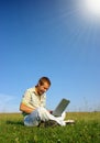 Happy student working with laptop on green meadow Royalty Free Stock Photo