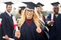 Happy students with diplomas showing thumbs up Royalty Free Stock Photo