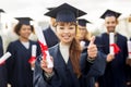 Happy students with diplomas showing thumbs up Royalty Free Stock Photo