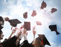 Students with diplomas throwing graduation hats in air outdoors