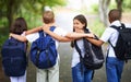 Happy students, friends and hug with backpack in park for unity, teamwork or walking to school together. Rear view of Royalty Free Stock Photo