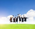 Happy  students in graduation gowns celebrating and jumping  on the grass field Royalty Free Stock Photo