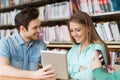 Happy students with tablet pc in library