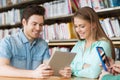 Happy students with tablet pc in library