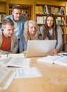 Happy students using laptop at desk in library Royalty Free Stock Photo
