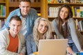 Happy students using laptop at desk in library Royalty Free Stock Photo