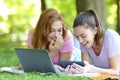 Happy students watching videos on smart phone in a park Royalty Free Stock Photo