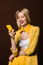 happy stylish blonde girl using yellow smartphone