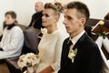 Happy stylish bride and elegant groom sitting at catholic wedding ceremony at church Royalty Free Stock Photo