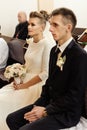 Happy stylish bride and elegant groom sitting at catholic wedding ceremony at church Royalty Free Stock Photo