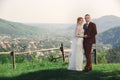 Happy stylish bride and groom running and having fun in mountains on summer sunny day. gorgeous newlywed couple laughing, true