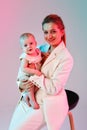 Happy stylish business woman in a light pantsuit with a baby in her arms on a white background. Mother and child. Shot with