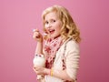 Happy stylish child isolated on pink eating farm organic yogurt