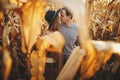 Happy stylish couple embracing and kissing in autumn corn field in warm sunset light Royalty Free Stock Photo