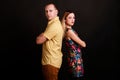 Happy stylish couple standing back each to other in confident pose on black background Royalty Free Stock Photo