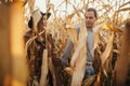 Happy stylish couple walking in autumn corn field in warm sunset light, among golden corn leaves Royalty Free Stock Photo