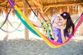 Happy stylish family with cute daughter relaxing in hammock on summer vacation in evening sun light on the beach. hipster couple w Royalty Free Stock Photo