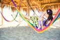 Happy stylish family with cute daughter relaxing in hammock on summer vacation in evening sun light on the beach Royalty Free Stock Photo