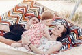 Happy stylish family with cute daughter relaxing in hammock on summer vacation in evening sun light on the beach. hipster couple Royalty Free Stock Photo