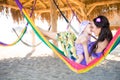 Happy stylish family with cute daughter relaxing in hammock on summer vacation in evening sun light on the beach. hipster couple w Royalty Free Stock Photo