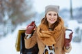 happy stylish female in brown hat and scarf in camel coat