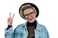 Happy stylish girl in fashionable jeans jacket and hat is showig peace sign Royalty Free Stock Photo