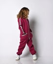 Happy stylish girl in a sports burgundy suit. a little schoolgirl stands with one hand in her pocket on a white Royalty Free Stock Photo