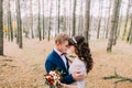 Happy stylish groom and his charming new wife posing in the autumn pine forest Royalty Free Stock Photo