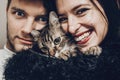 happy stylish hipster family hugging with their cat. man and woman holding kitty and having fun and taking selfie, happy family m Royalty Free Stock Photo