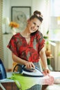 Happy stylish housewife ironing while talking on phone Royalty Free Stock Photo