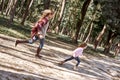Happy, stylish little curly girl is running with her beautiful mother in forest