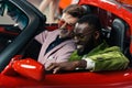 happy stylish multicultural men sitting in new car