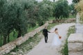 Happy stylish smiling couple walking in Tuscany, Italy on their wedding day. The bride and groom walk down the street by Royalty Free Stock Photo