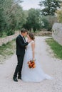 Happy stylish smiling couple walking in Tuscany, Italy on their wedding day. The bride and groom walk down the street by Royalty Free Stock Photo