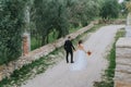 Happy stylish smiling couple walking in Tuscany, Italy on their wedding day. The bride and groom walk down the street by Royalty Free Stock Photo
