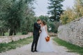 Happy stylish smiling couple walking in Tuscany, Italy on their wedding day. The bride and groom walk down the street by Royalty Free Stock Photo