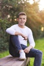 Stylish teenager sitting on a wooden bench on a city park Royalty Free Stock Photo