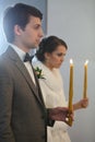 Bride and groom standing at wedding ceremony. Happy stylish wedding couple holding candles with light under golden Royalty Free Stock Photo