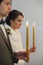 Bride and groom standing at wedding ceremony. Happy stylish wedding couple holding candles with light under golden Royalty Free Stock Photo