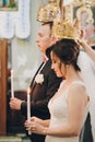 Happy stylish wedding couple holding candles with light under golden crowns during holy matrimony in church. Bride and groom Royalty Free Stock Photo