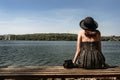 happy stylish woman hipster sitting on wooden bench at sunny shore near water, summer travel concept, space for text Royalty Free Stock Photo