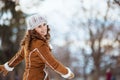 Happy stylish woman rejoicing outside in city park in winter