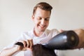 Happy stylist with fan making blow-dry at salon