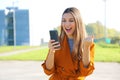 Happy success woman celebrating outdoor cheering and raising her fist up in exultation. Excited fashion woman watching her phone Royalty Free Stock Photo