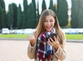 Happy success woman celebrating outdoor cheering and raising her fist up in exultation. Excited fashion woman watching her phone