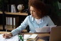 Happy successful African American business woman owner of new business analyzes sales report while sitting in modern office Royalty Free Stock Photo