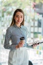 Happy successful Asian businesswoman holding a cup of coffee and tiger skin in front of her office desk. Royalty Free Stock Photo