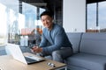 Happy and successful asian working in office with laptop, businessman looking at camera and smiling, holding phone Royalty Free Stock Photo