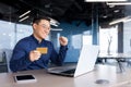 Happy and successful businessman in office making online payments inside building, asian man using bank credit card and Royalty Free Stock Photo